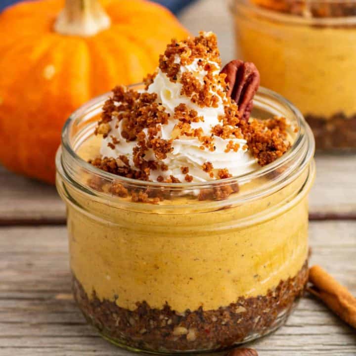 An orange pumpkin sits beside an individually sized Pumpkin Delight dessert topped with gingersnap crumbs and pecans.