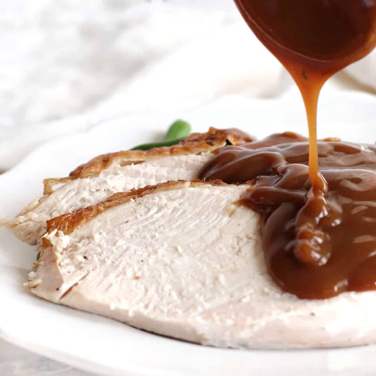 Pouring gravy over sliced turkey breast. 