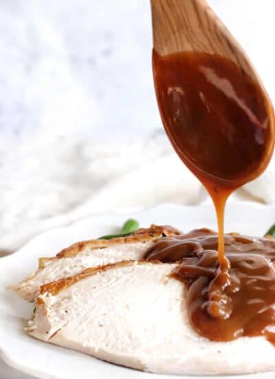 Sliced turkey on a plate with gravy drizzled on.