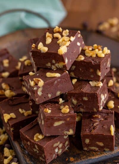 Chocolate Walnut Fudge cut in squares and piled on a plate.
