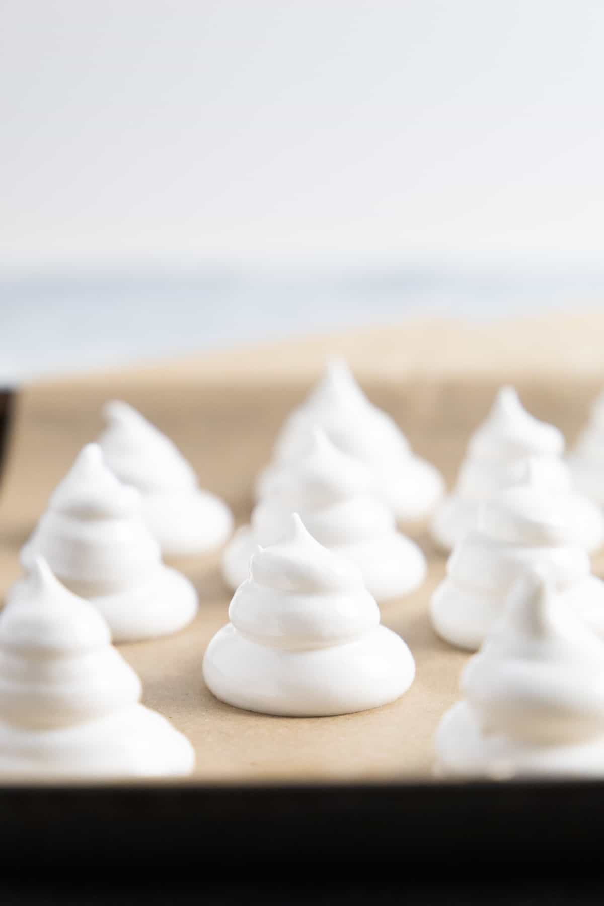 side view of meringues on a lined baking sheet