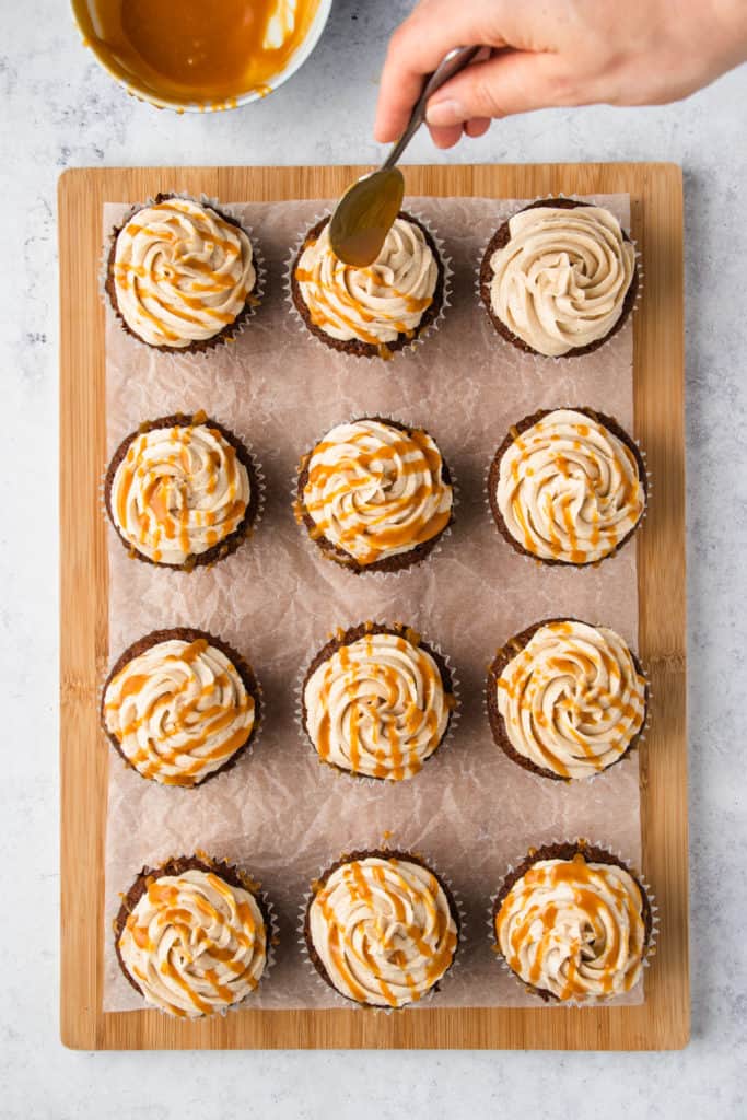 putting caramel drizzle on a cupcake