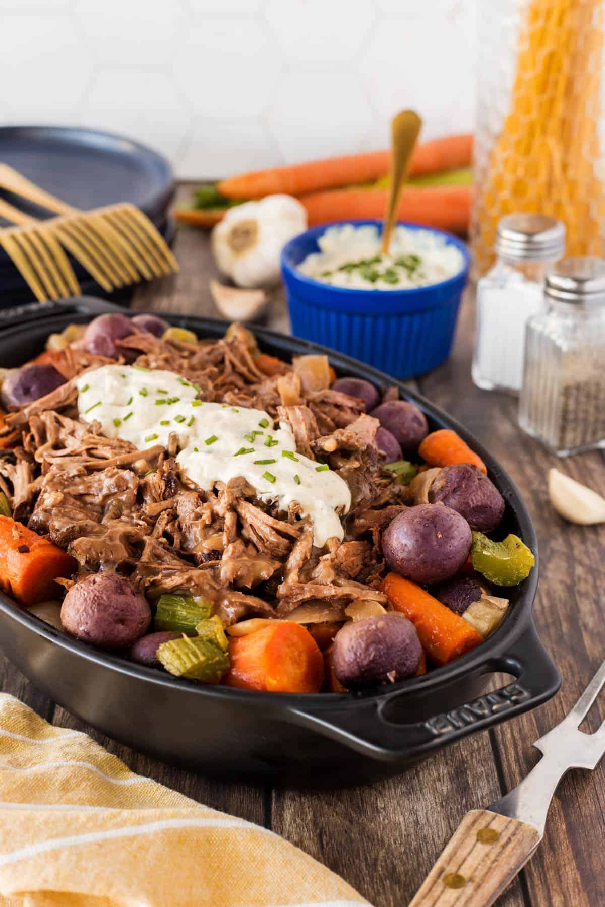 Served slow cooker roast beef with potatoes and carrots in a casserole dish. 