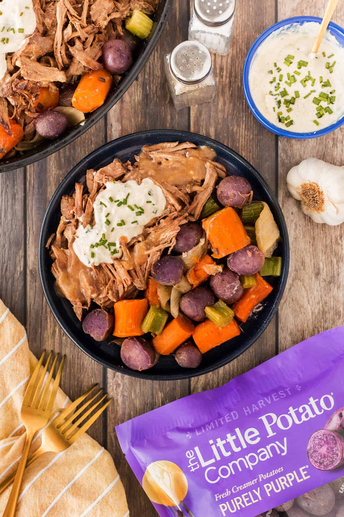 Overhead plated roast beef dinner with a bag of Purely Purple Little Potatoes. 