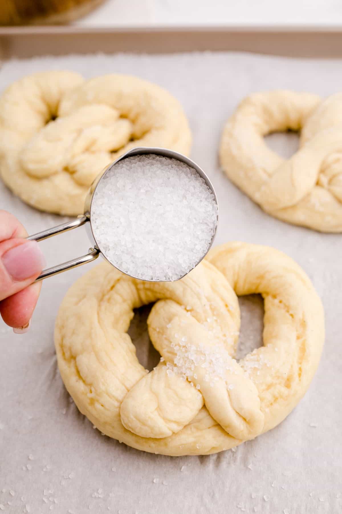 Sprinkling Kosher salt onto a soft pretzel before baking