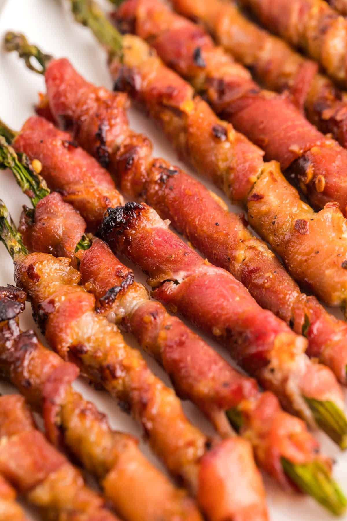 Close-up of bacon wrapped asparagus on a white platter. 