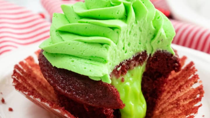 Showing the ooey gooey inside of a Grinch Cupcake with green pudding oozing out.