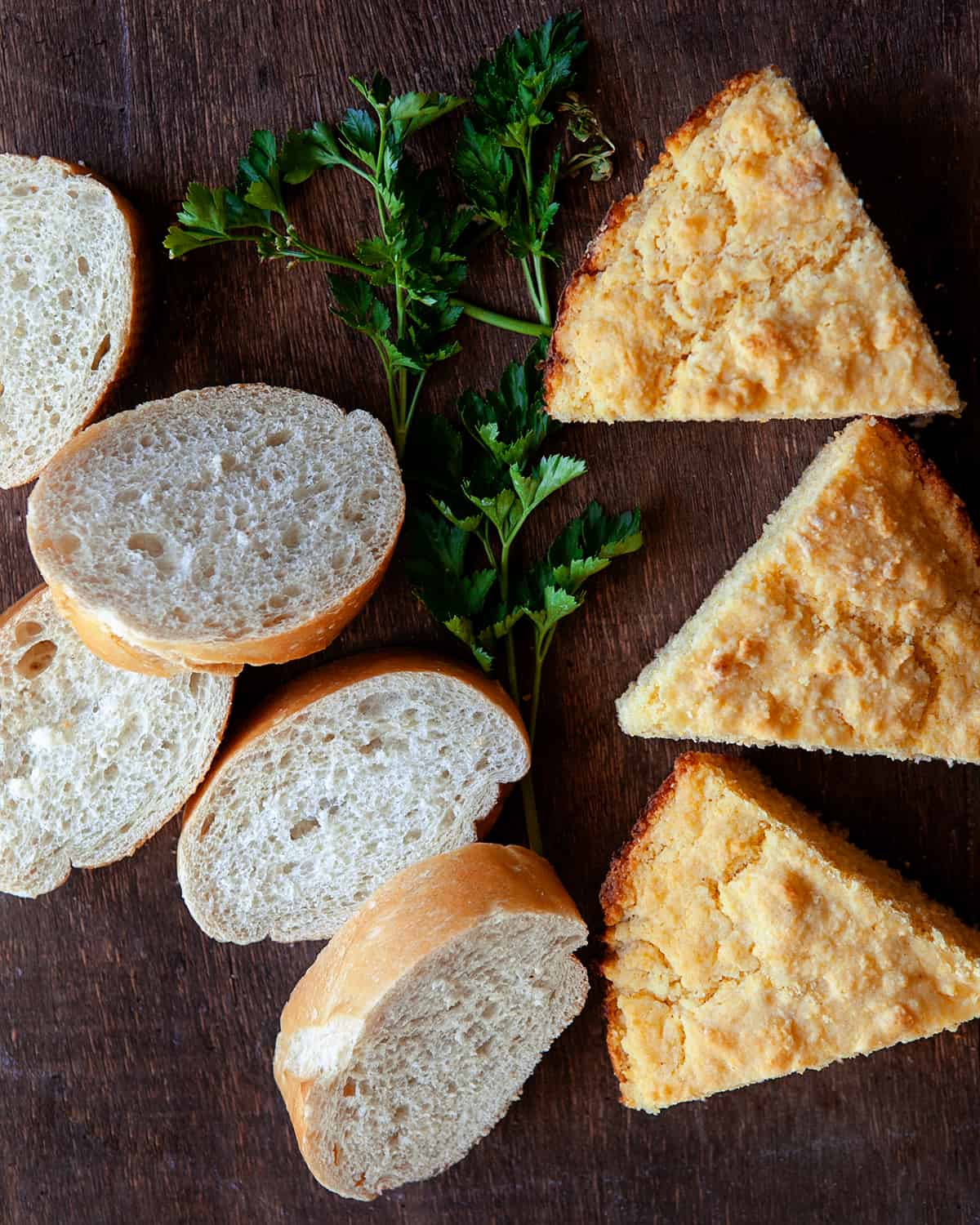 Cornbread and white bread on a wooden board with parsley 