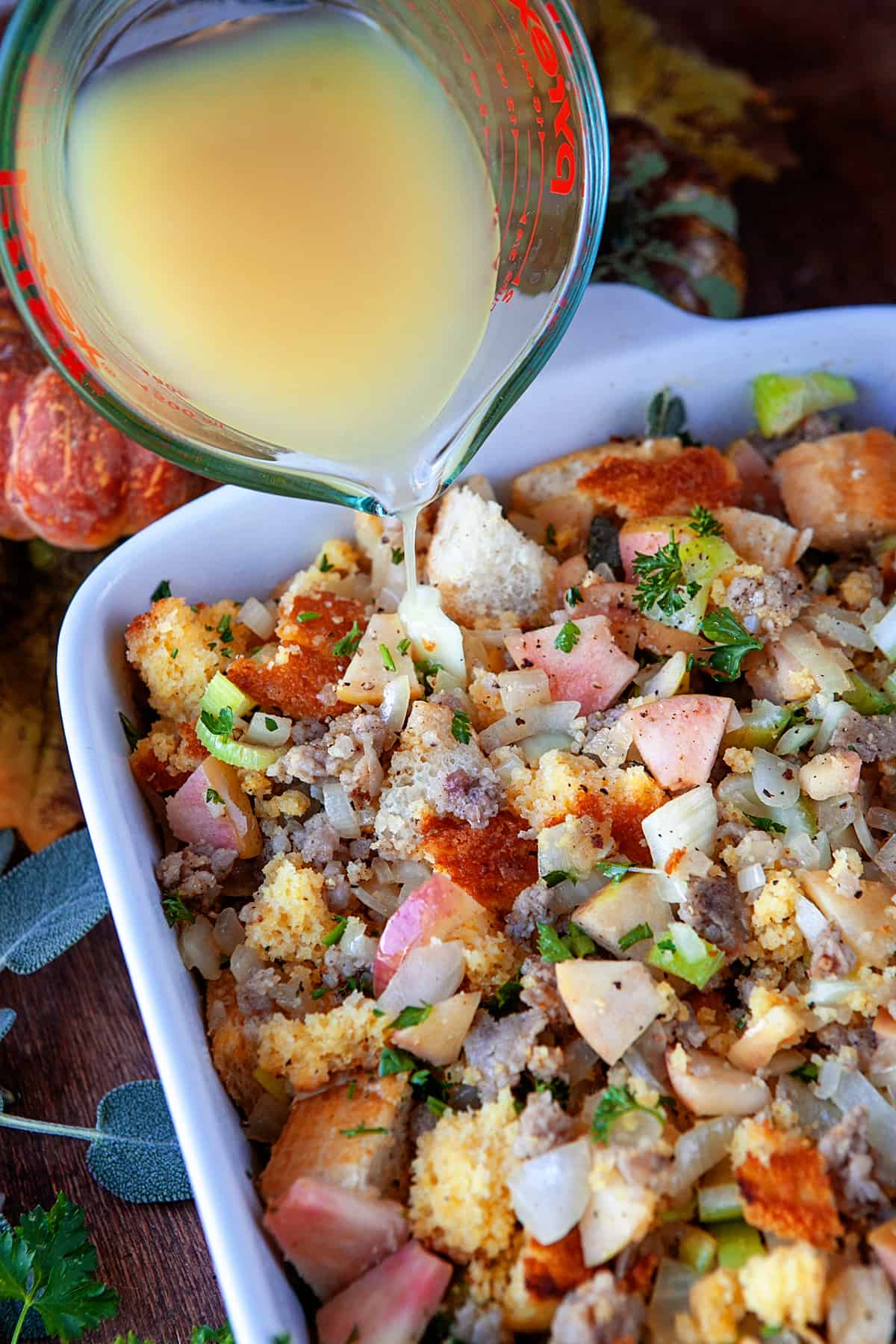 Pouring chicken broth over the dressing in a casserole dish. 