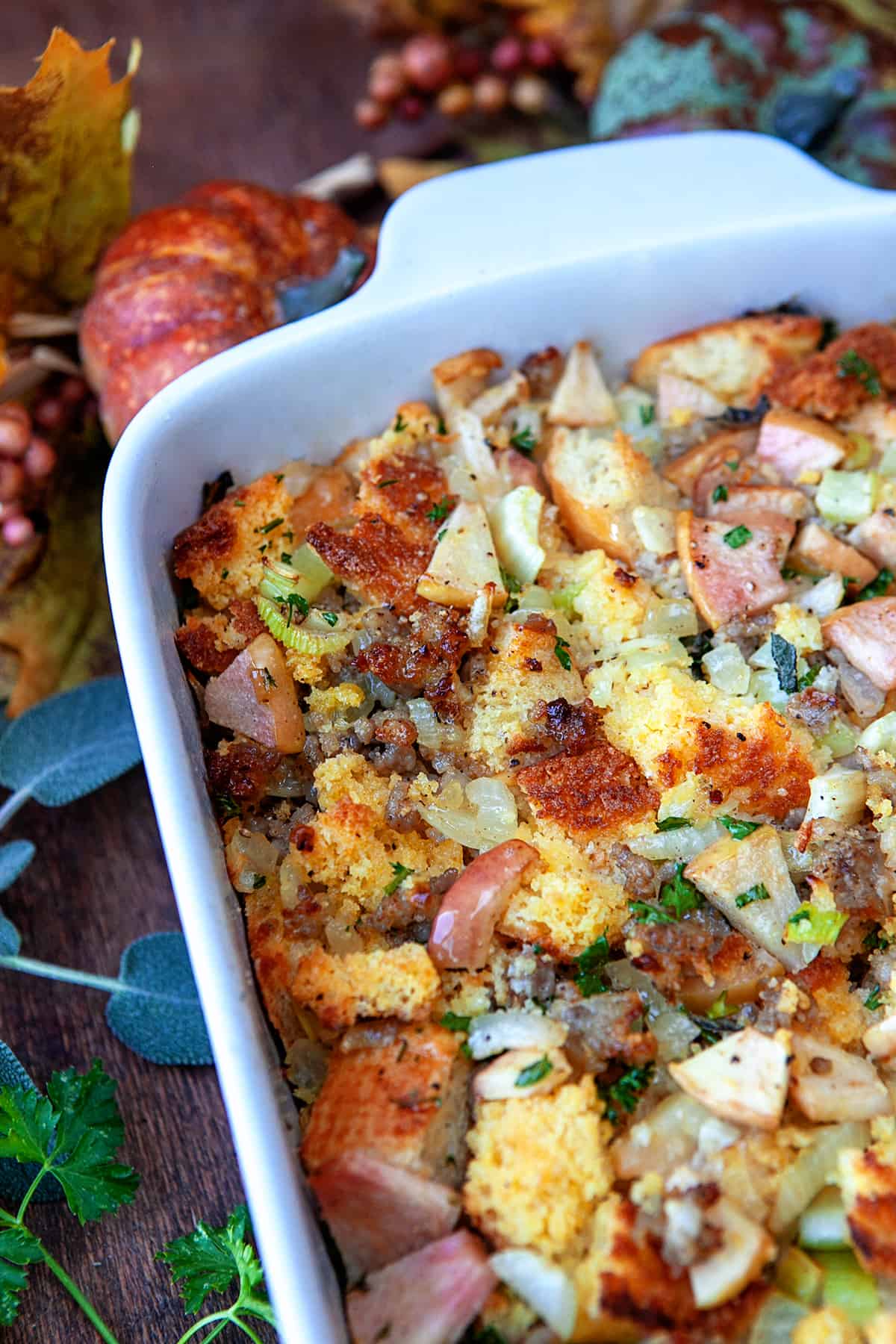 Cornbread dressing in a casserole dish with fall decor around it. 