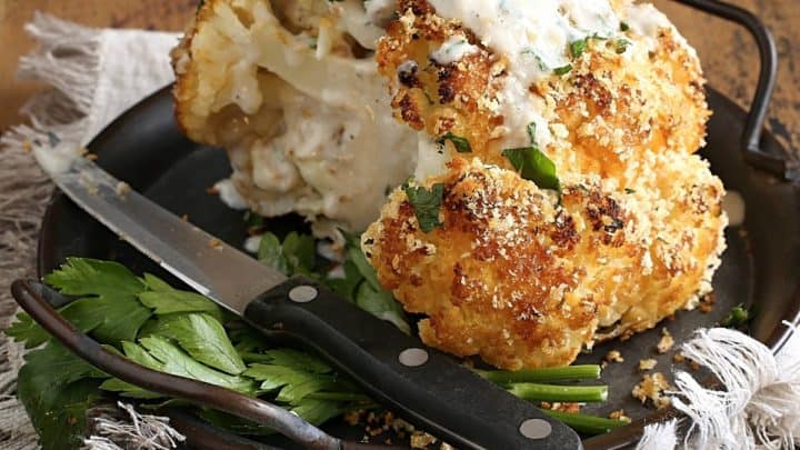 Whole Roasted Cauliflower with Parmesan Cream Sauce on a plate with a knife