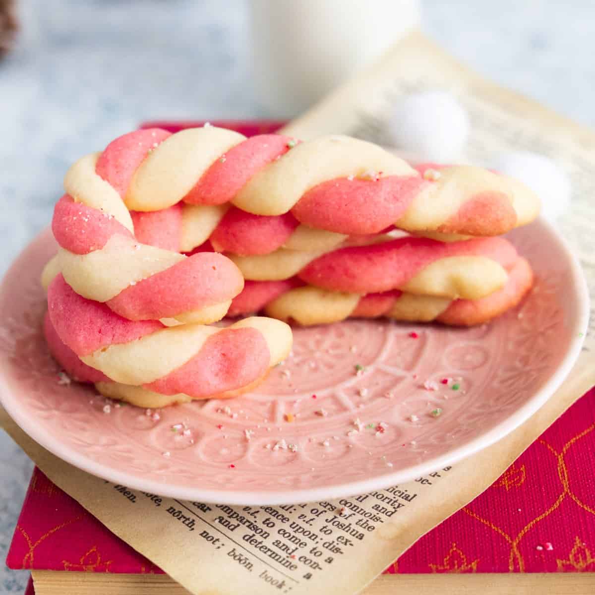 Stacked candy cane cookies on a pink plate.