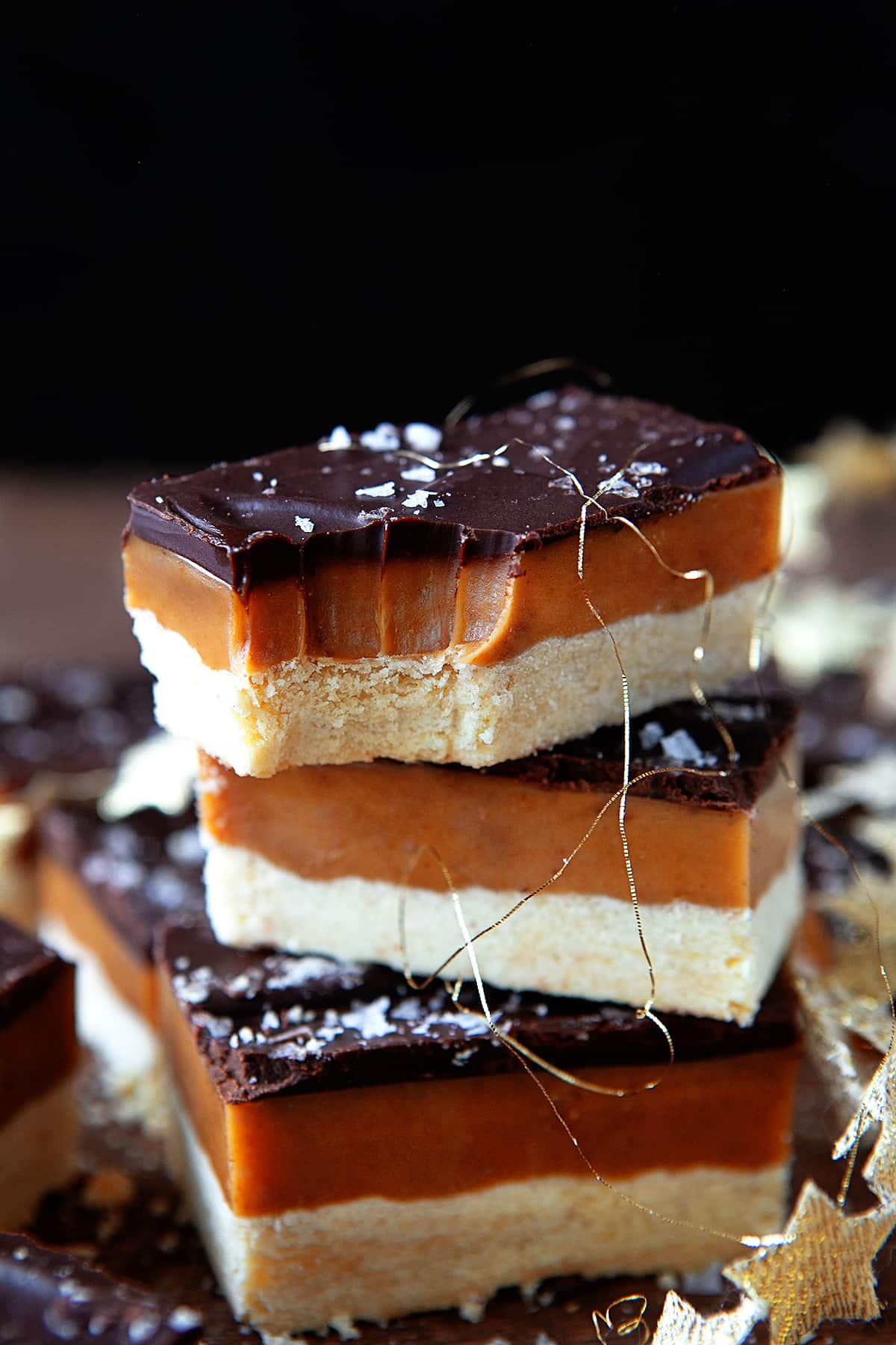 Millionaire Shortbread stacked with the top one having a bite taken. 