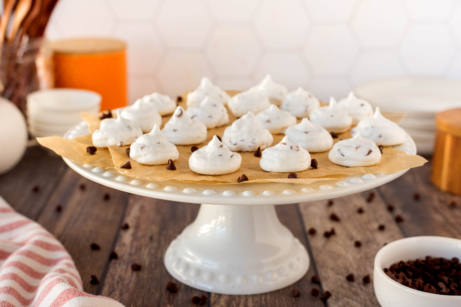 Mini Chocolate Chip Meringue Cookies on a white serving platter lined with parchment paper.