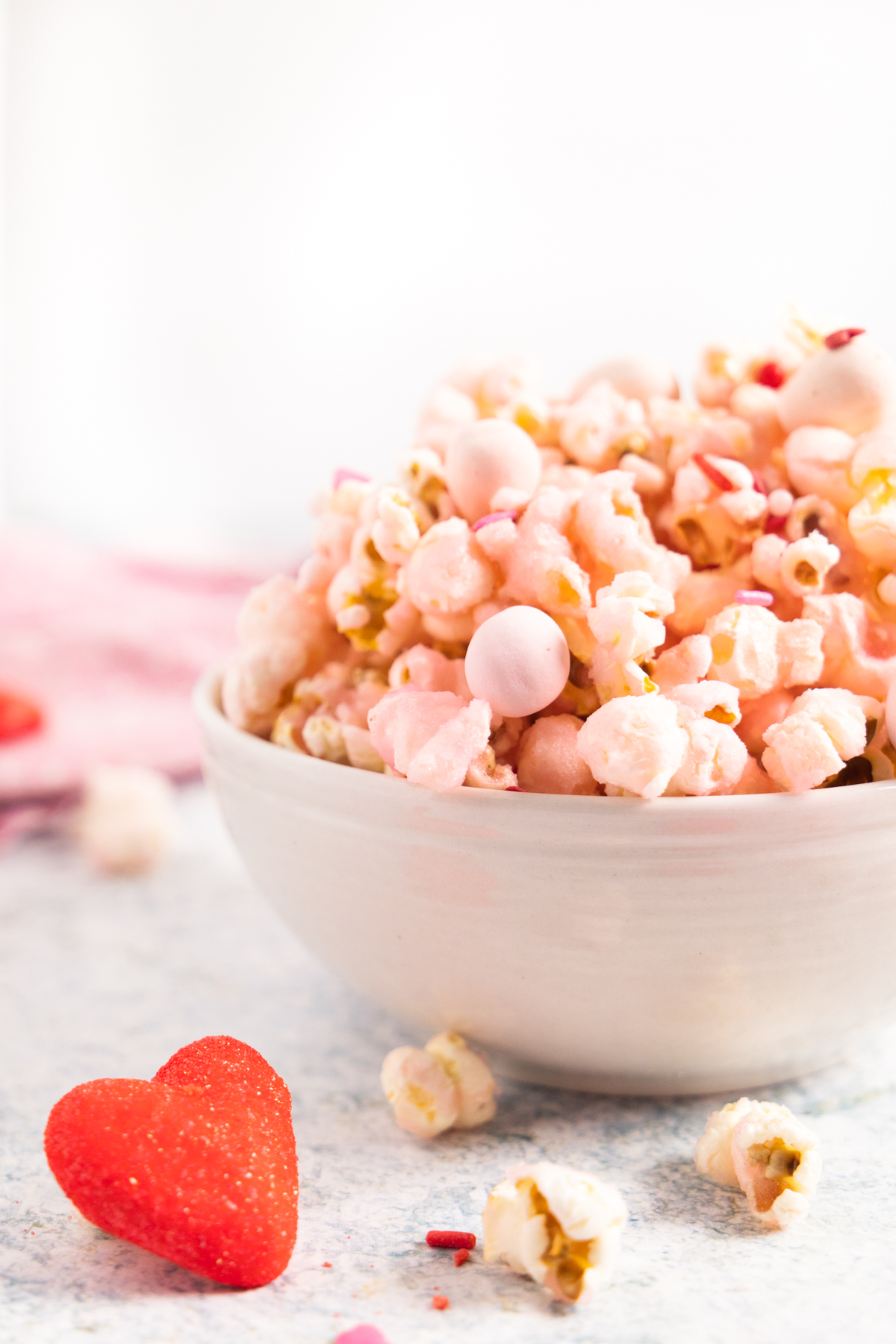 Side view of pink popcorn in a white bowl with marshmallow on the side