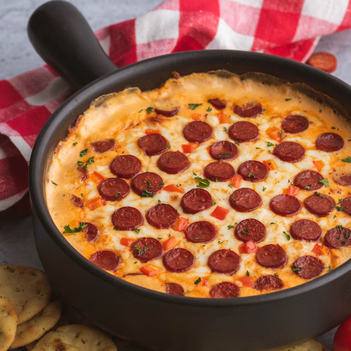 A black baking dish filled with bubbling hot cheesy pepperoni pizza dip.
