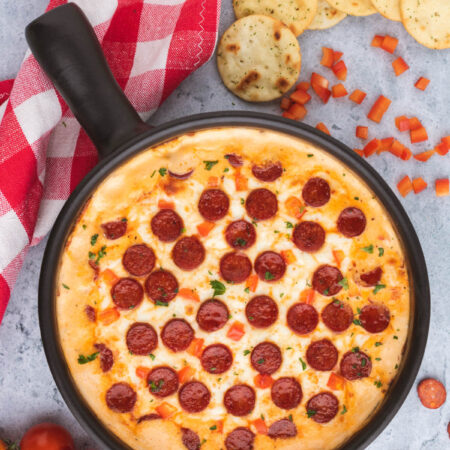 A black baking dish filled with bubbling hot cheesy pepperoni pizza dip.