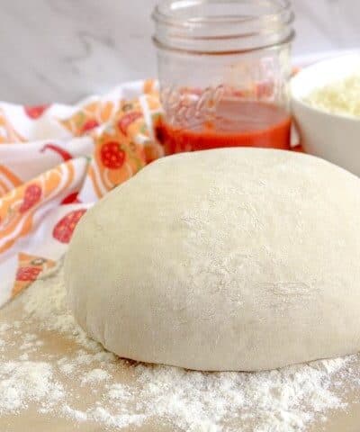 Bread Machine Pizza Dough on a floured counter with sauce and mozzarella in the background