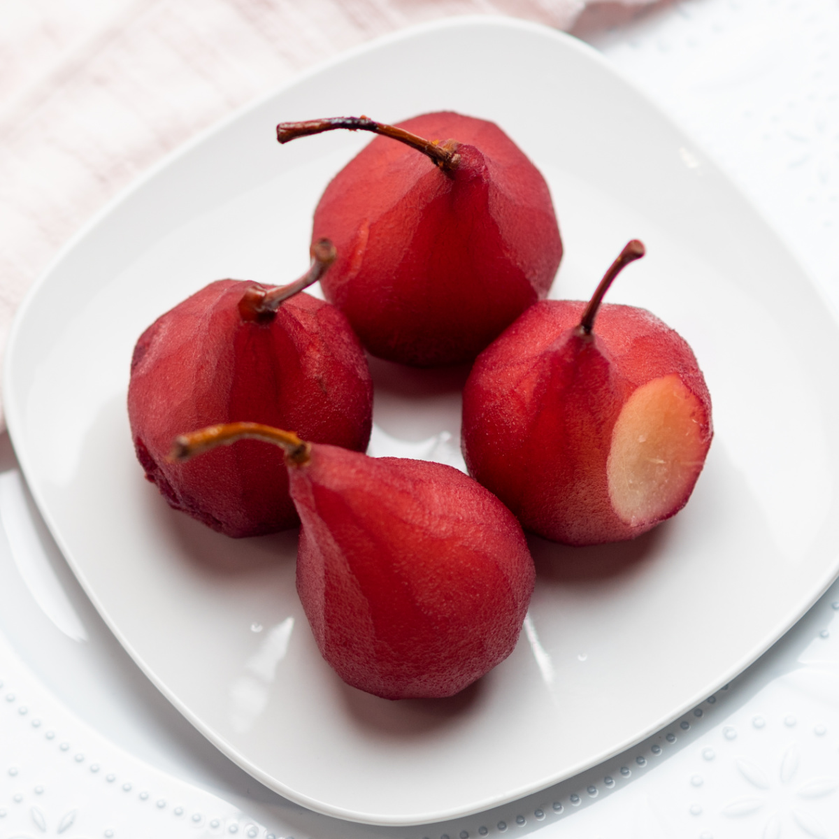 Close-up of an overhead shot of red wine poached pears on a white plate. 