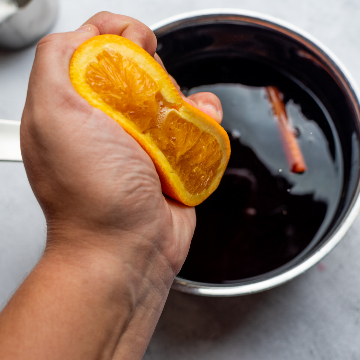 Squeezing orange juice into a pot of red wine mixture