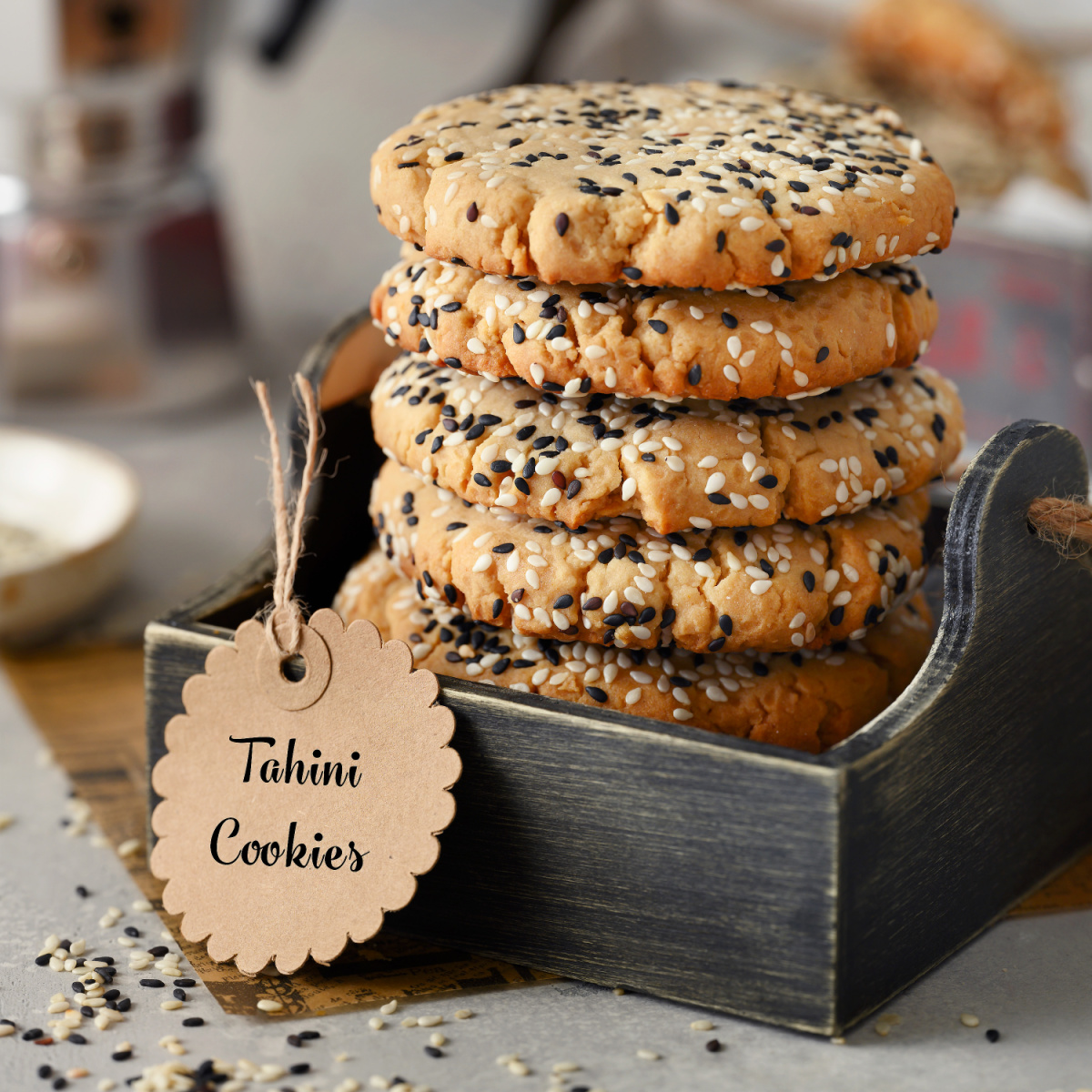 Tahini cookies stacked in a small box with a tag. 