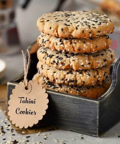 Stacked Sesame Tahini Cookies in a small box with a tag.