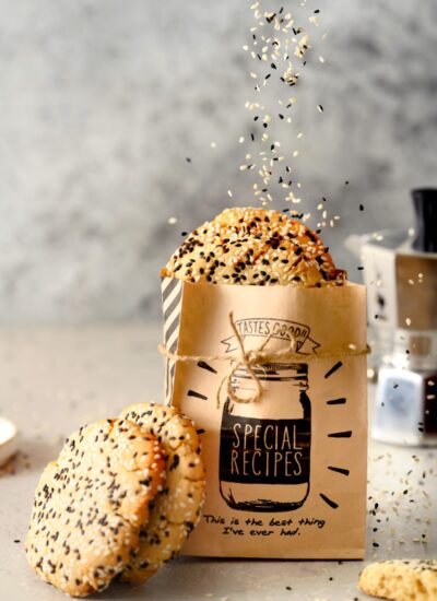 Cookies in a bag and leaning against the bag. Sprinkles of sesame seeds falling onto the bagged cookies.