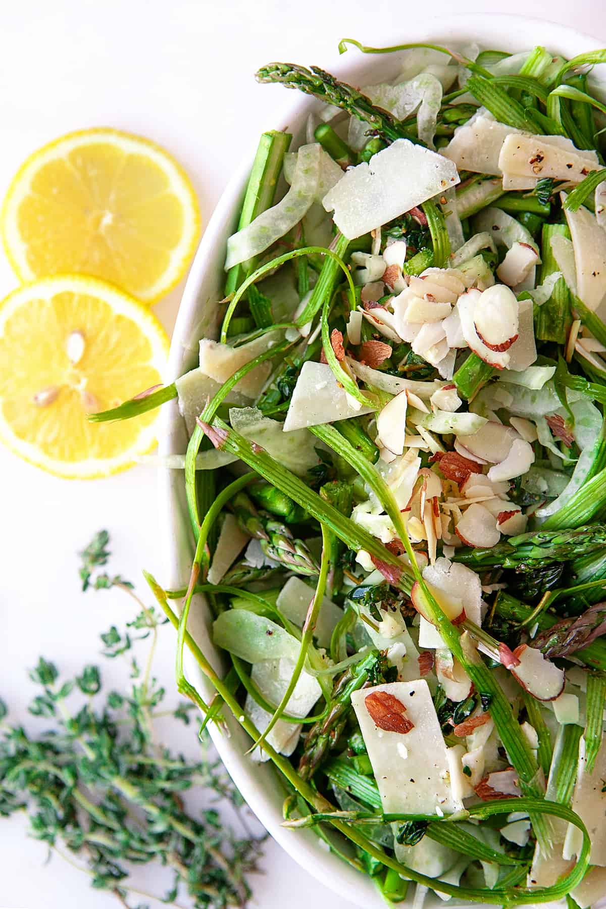Overhead of the partial bowl of Fennel Asparagus Salad, lemon slices on the side. 