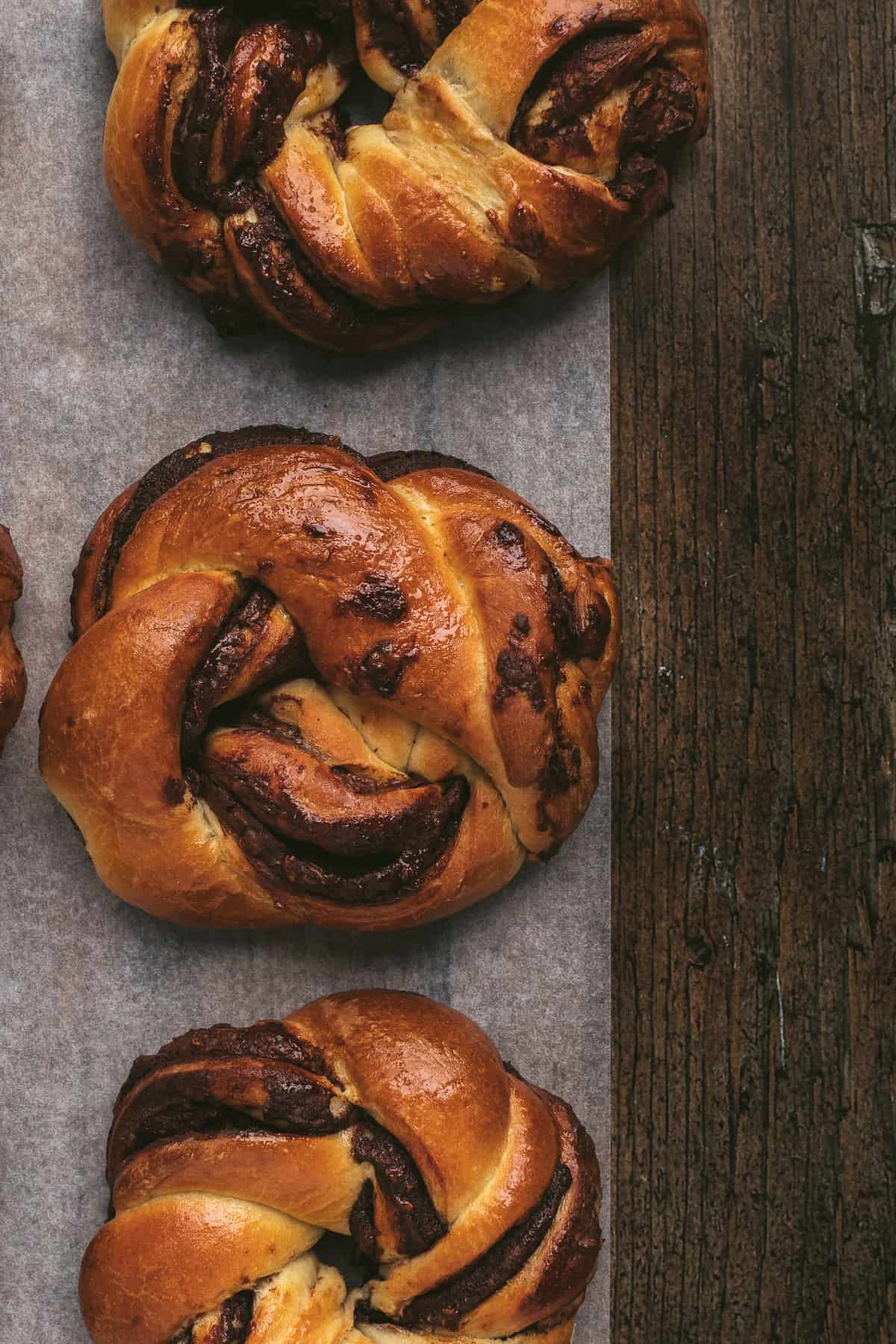 Chocolate Babka Buns lined up on parchment paper.