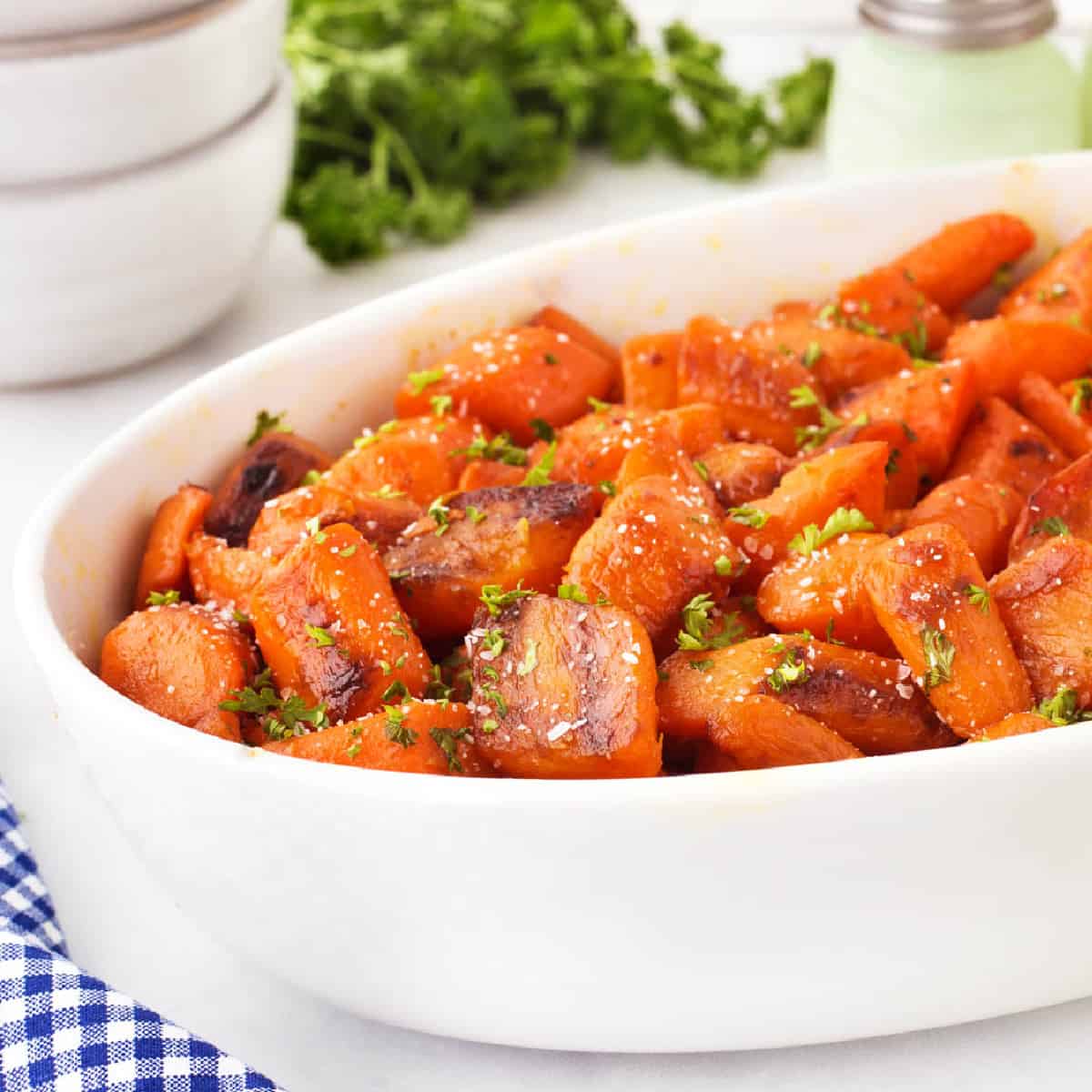 Square photo of caramelized carrots in a large white bowl. 