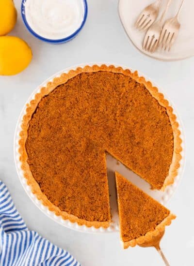 Overhead shot of treacle tart with a slice being taken out.