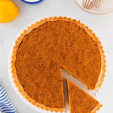 Overhead shot of treacle tart with a slice being taken out.