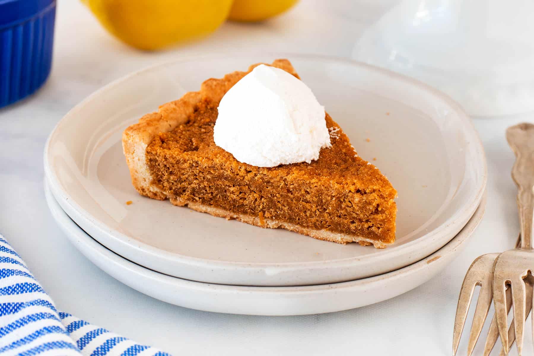 Horizontal photo of a slice of treacle tart on a plate with whipped cream. 