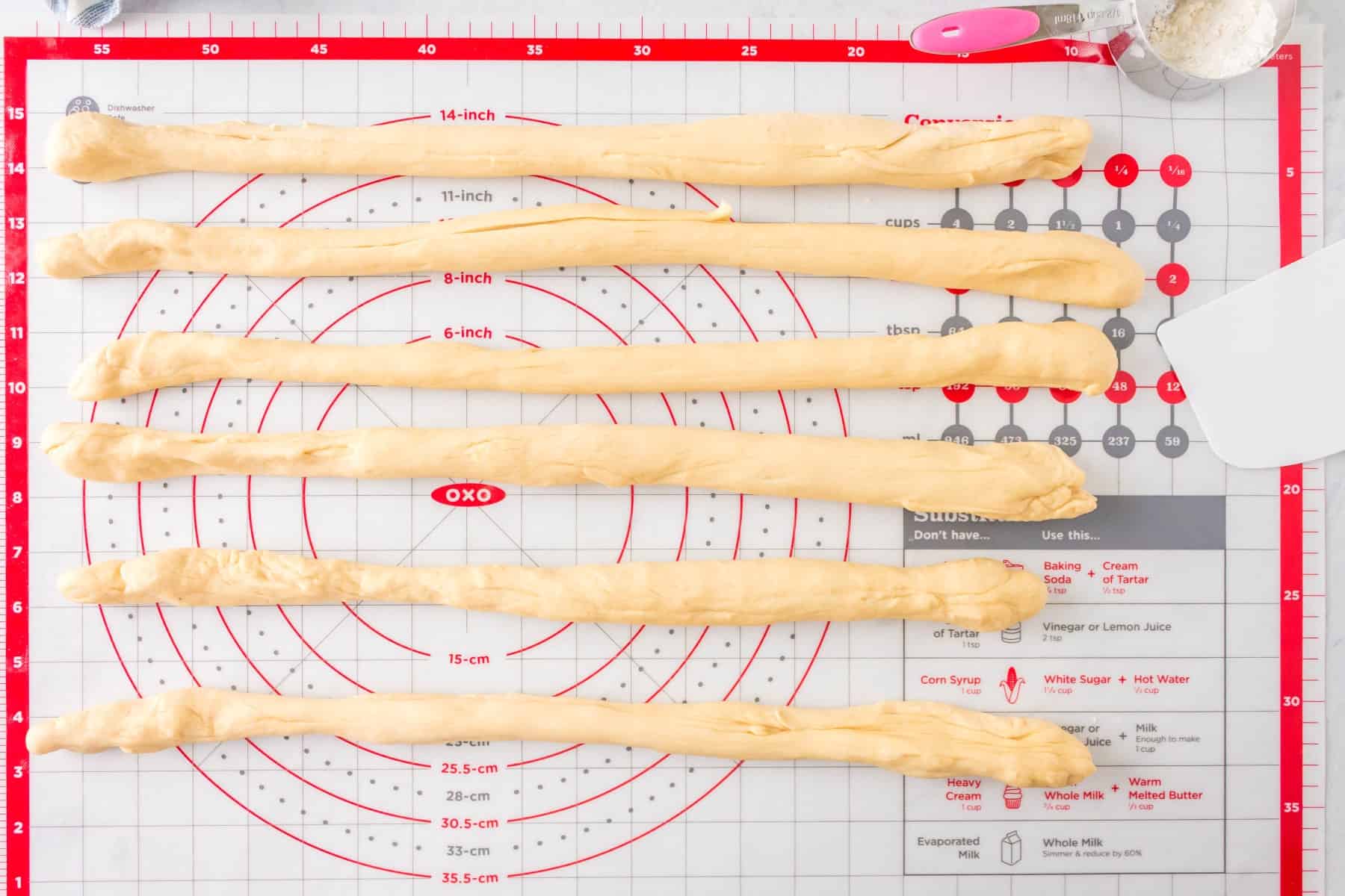 Six strands of dough laid out on a pastry mat. 