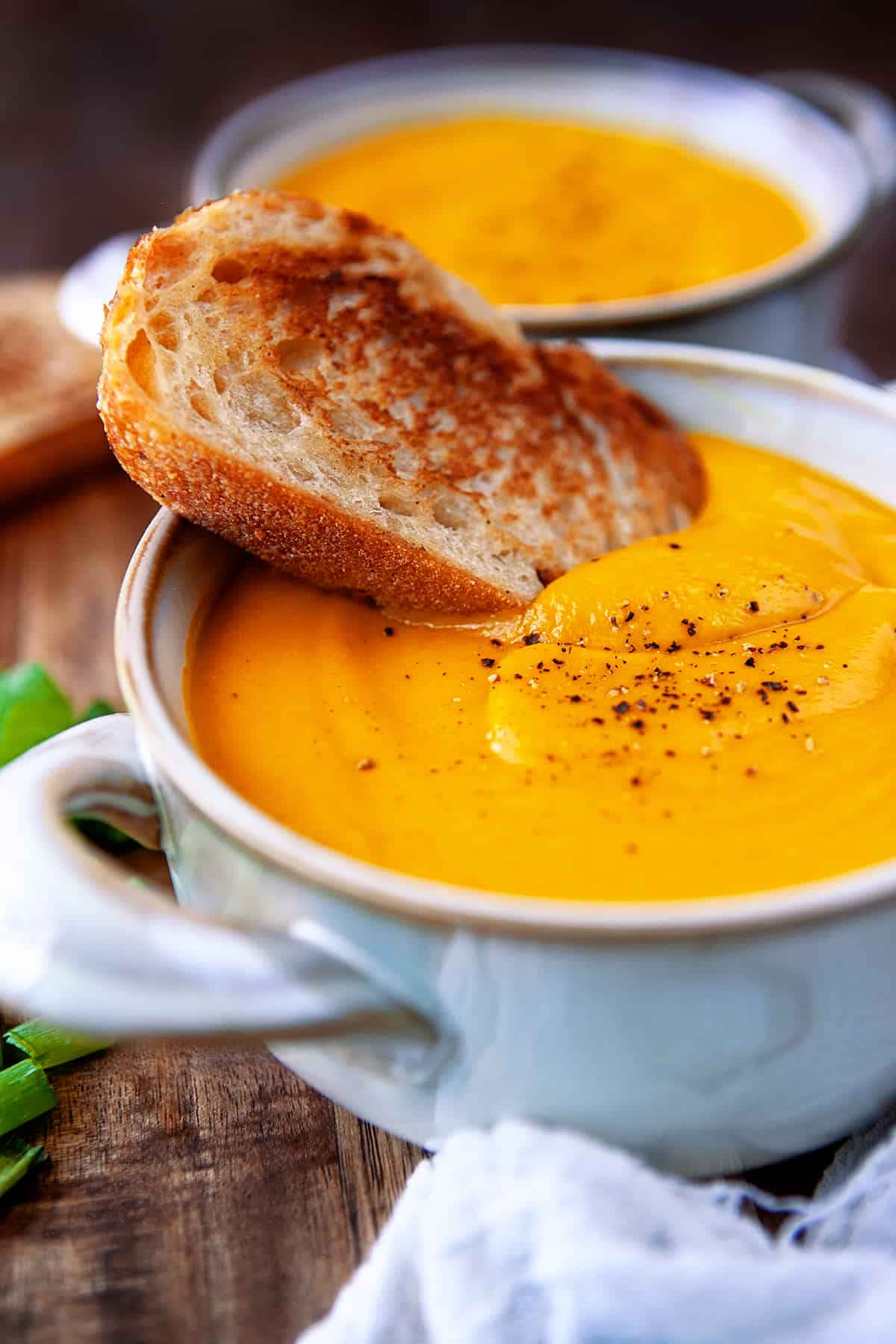 Bowl of carrot ginger soup with toasted artisan bread in the soup