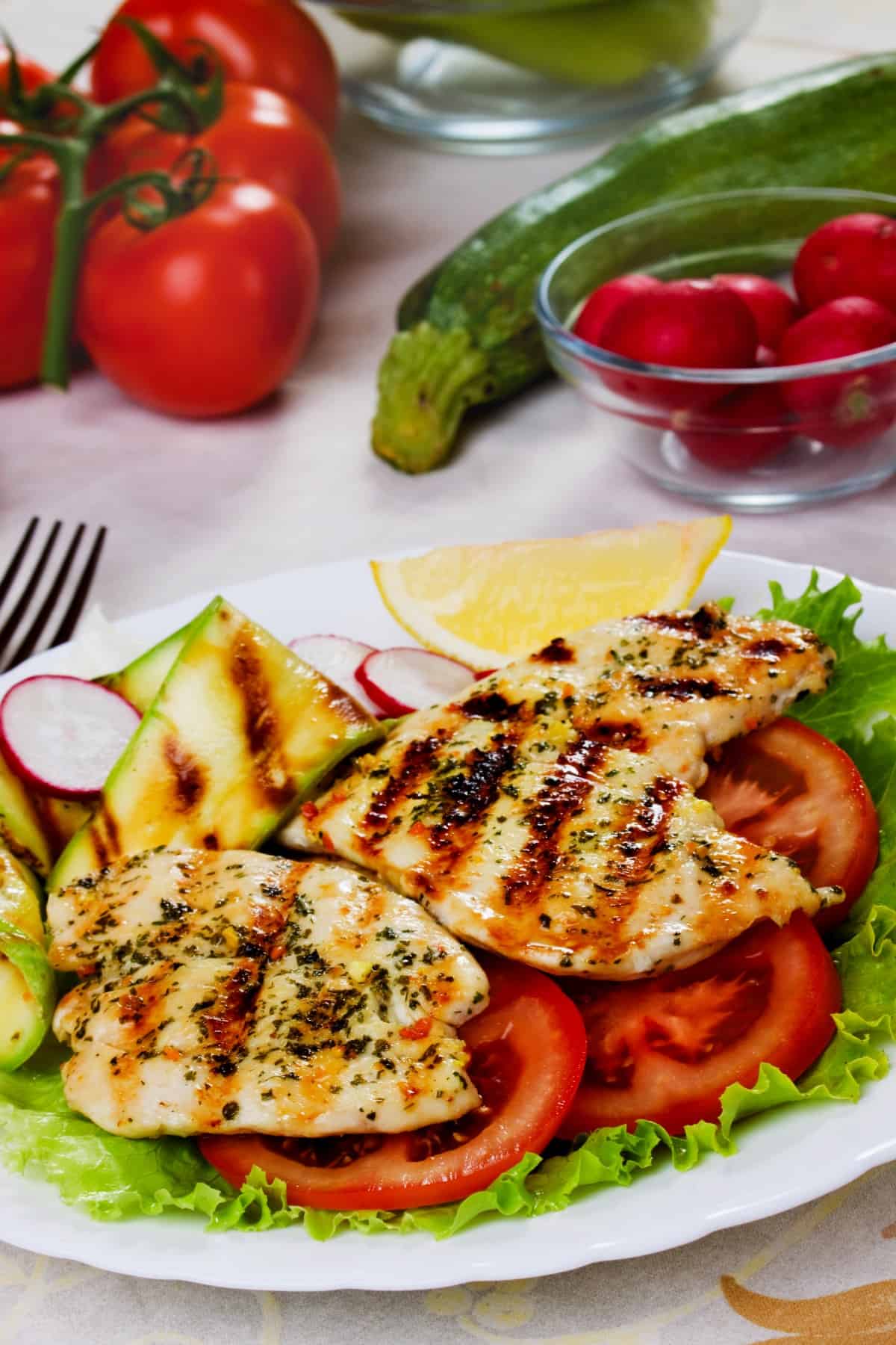 Grilled chicken breasts with tomato, lettuce and zucchini