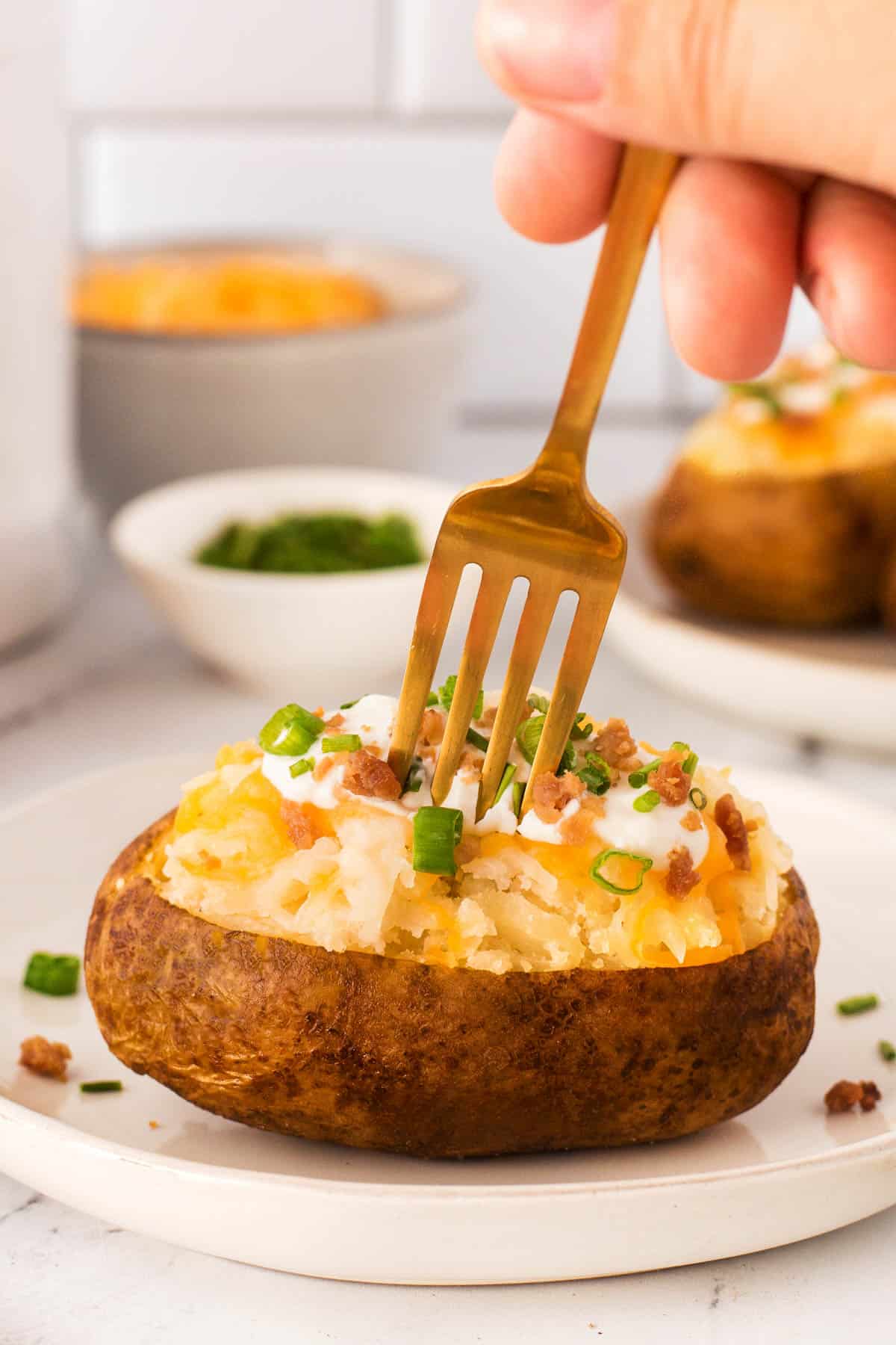 Sticking a fork into a Fluffy Crock Pot Baked Potatoes with classic toppings. 