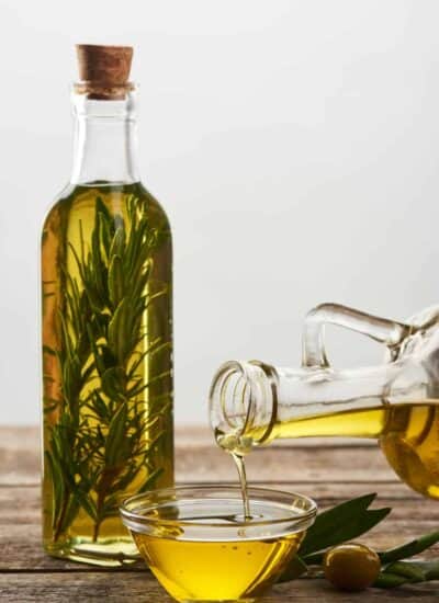Pouring olive oil from bottle into glass bowl.