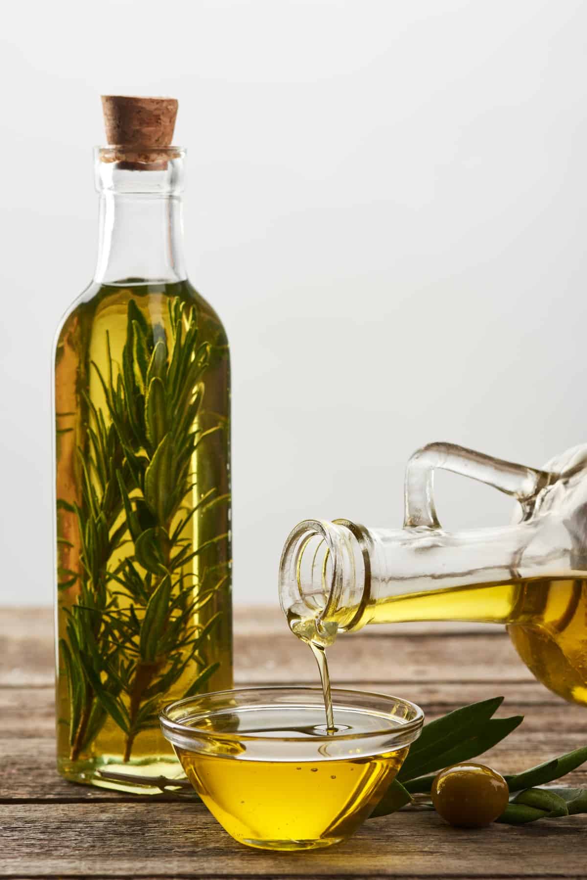 Pouring olive oil from bottle into glass bowl.