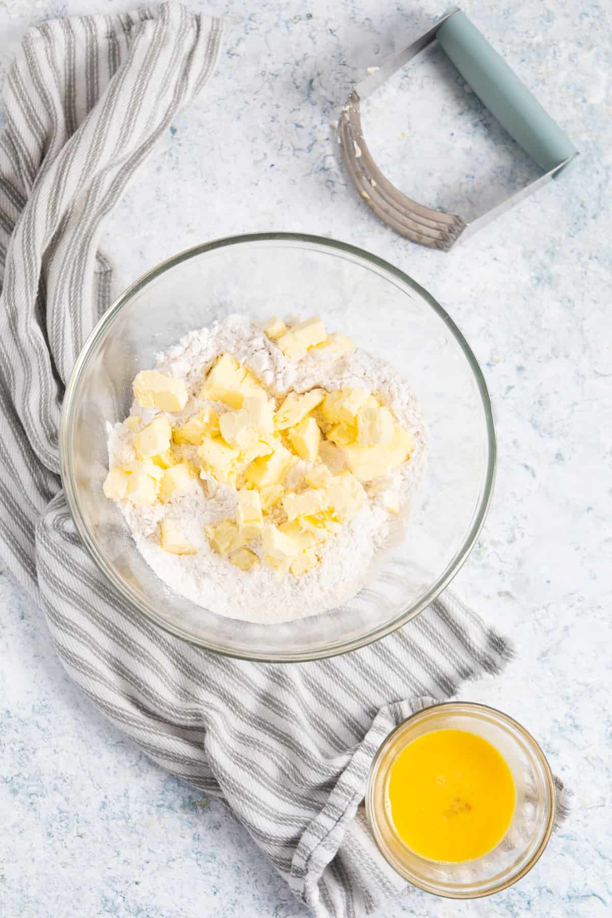 Butter and flour in a transparent bowl with a beaten egg in a small ramekin on the side.