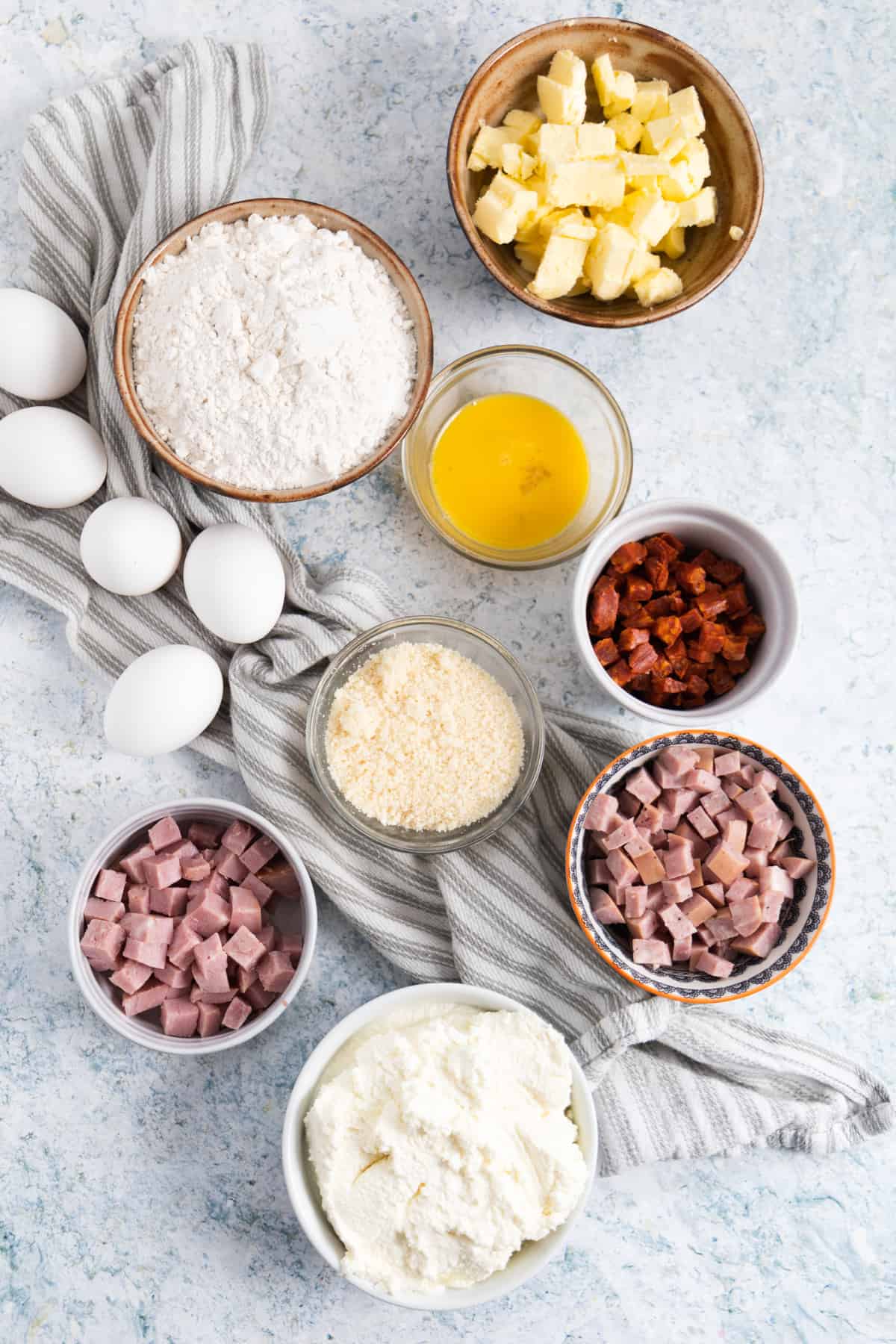All the ingredients needed to make an Italian Easter pie: eggs, flour, butter, parmesan, ricotta, ham, sausage, chorizo.