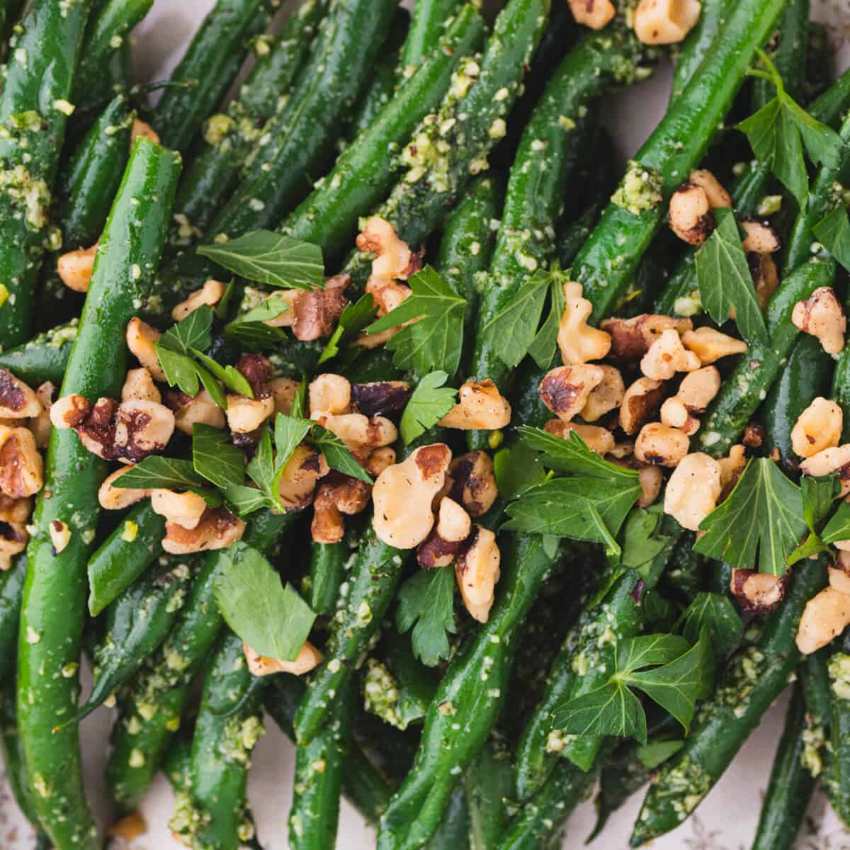 Vibrant Pesto Green Beans tossed with pesto and topped with chopped walnuts and fresh parsley.