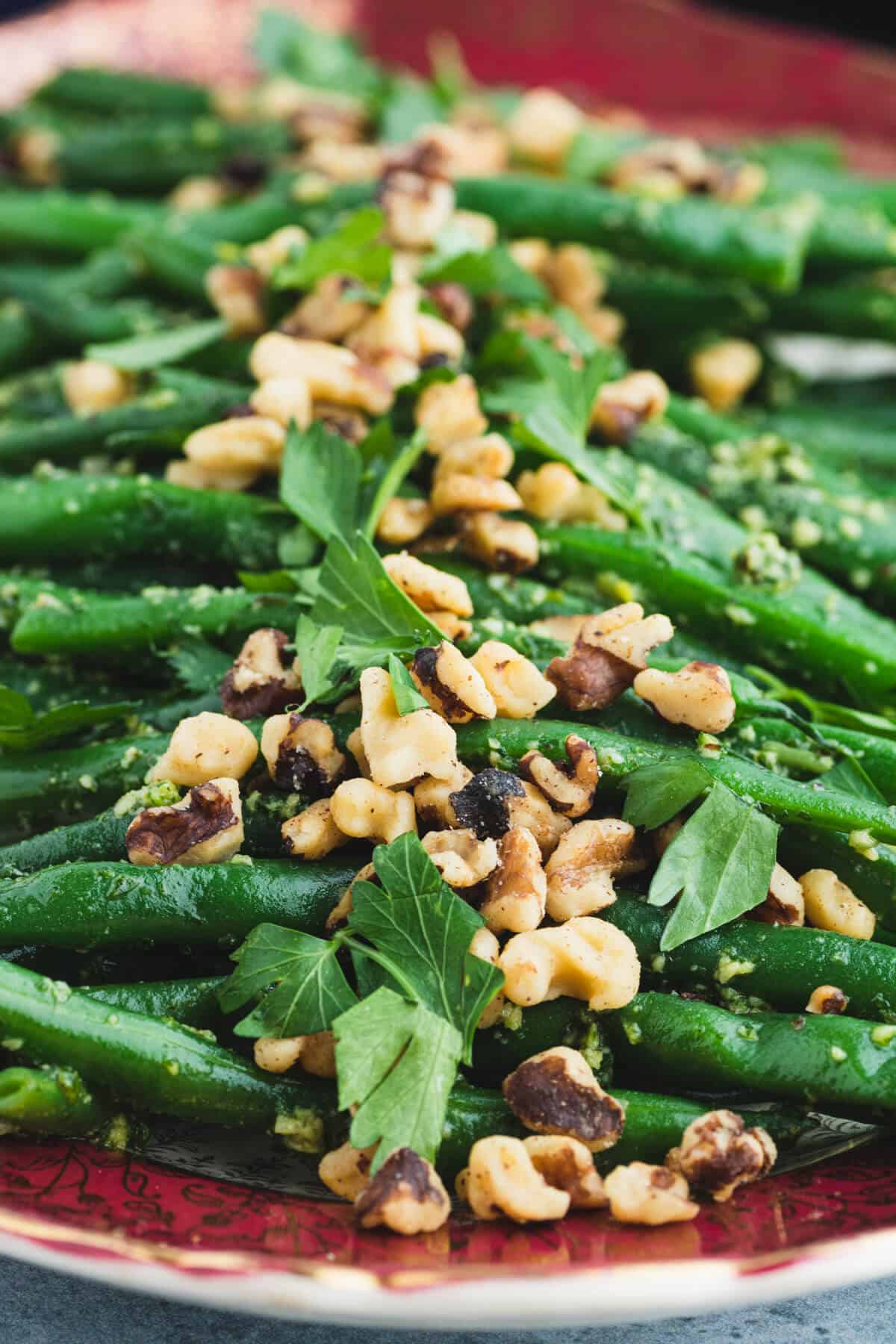 Close up of vibrant Pesto Green Beans tossed with pesto and topped with chopped walnuts and fresh parsley.