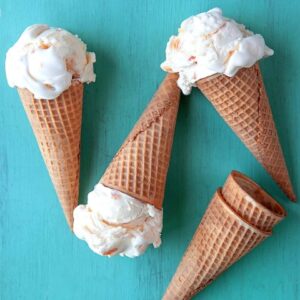 Overhead view of ice cream in cones lying down on an aqua back board.