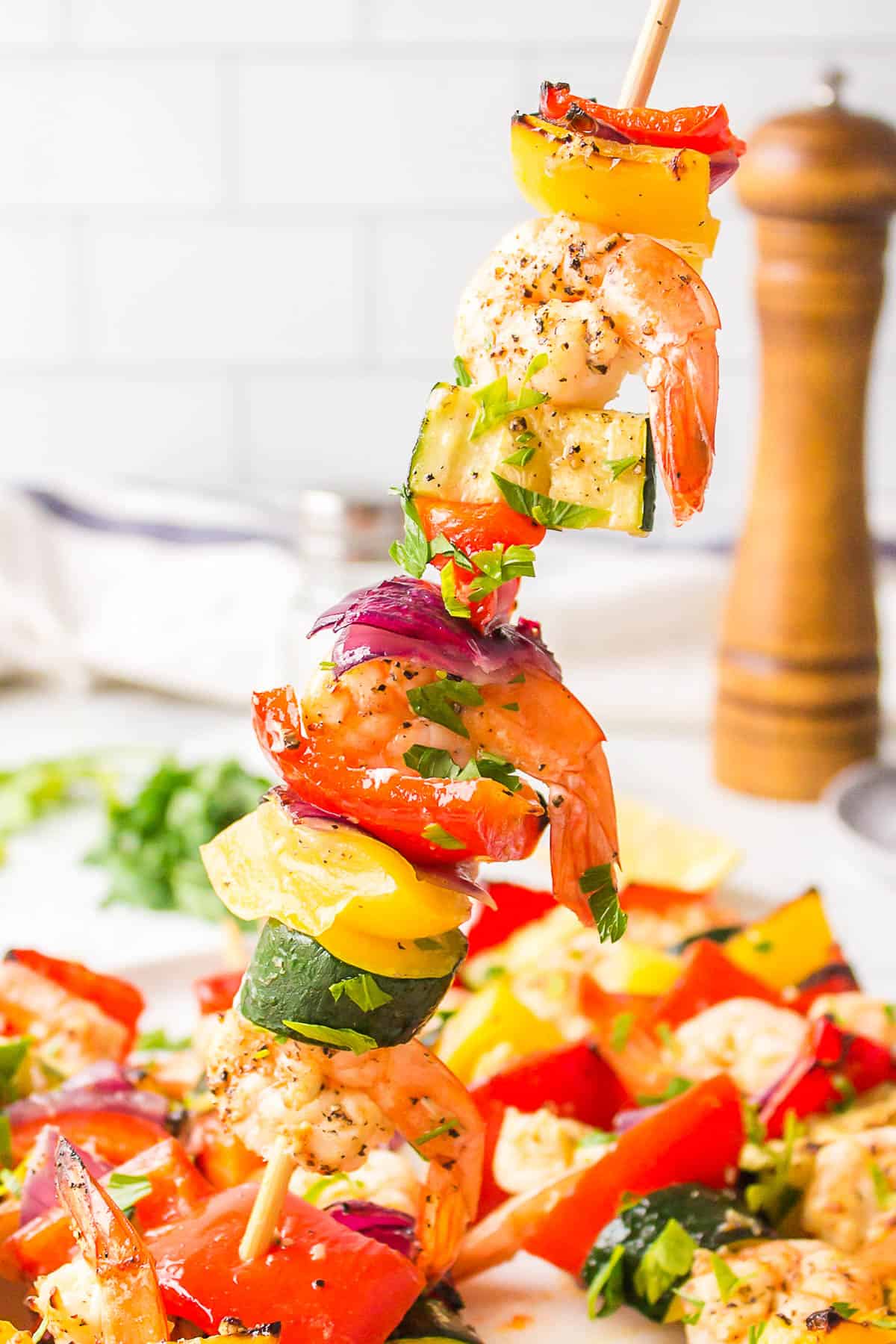 Holding up a shrimp skewer with veggies. 