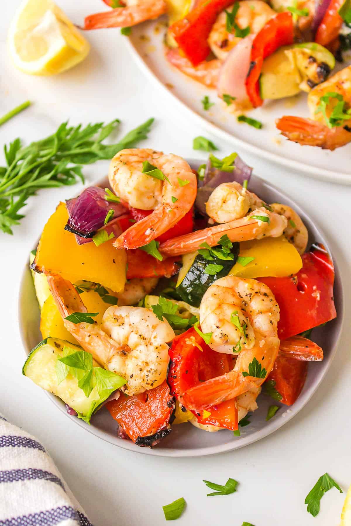 Shrimp and veggies removed from a skewer and onto a plate. 