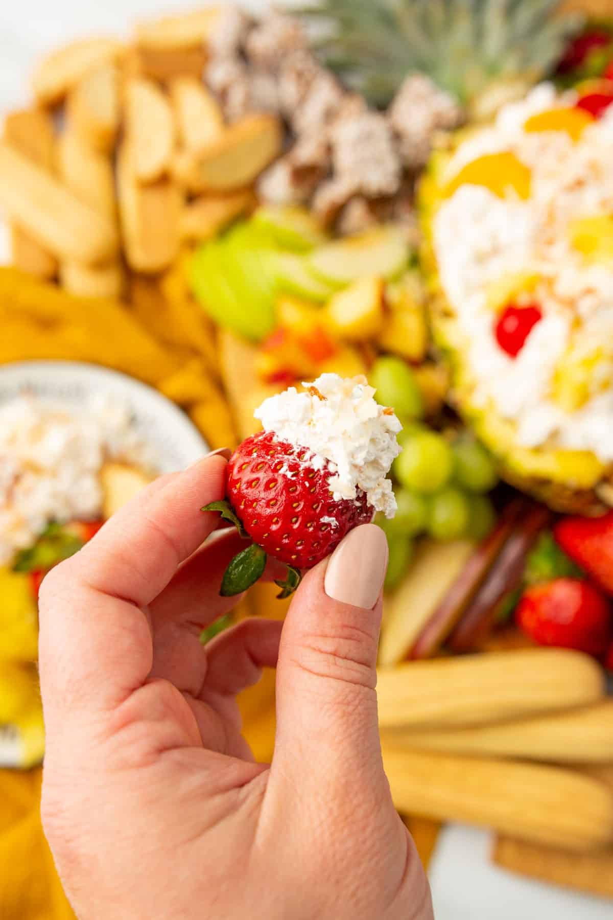 Holding a strawberry with dip on it. 