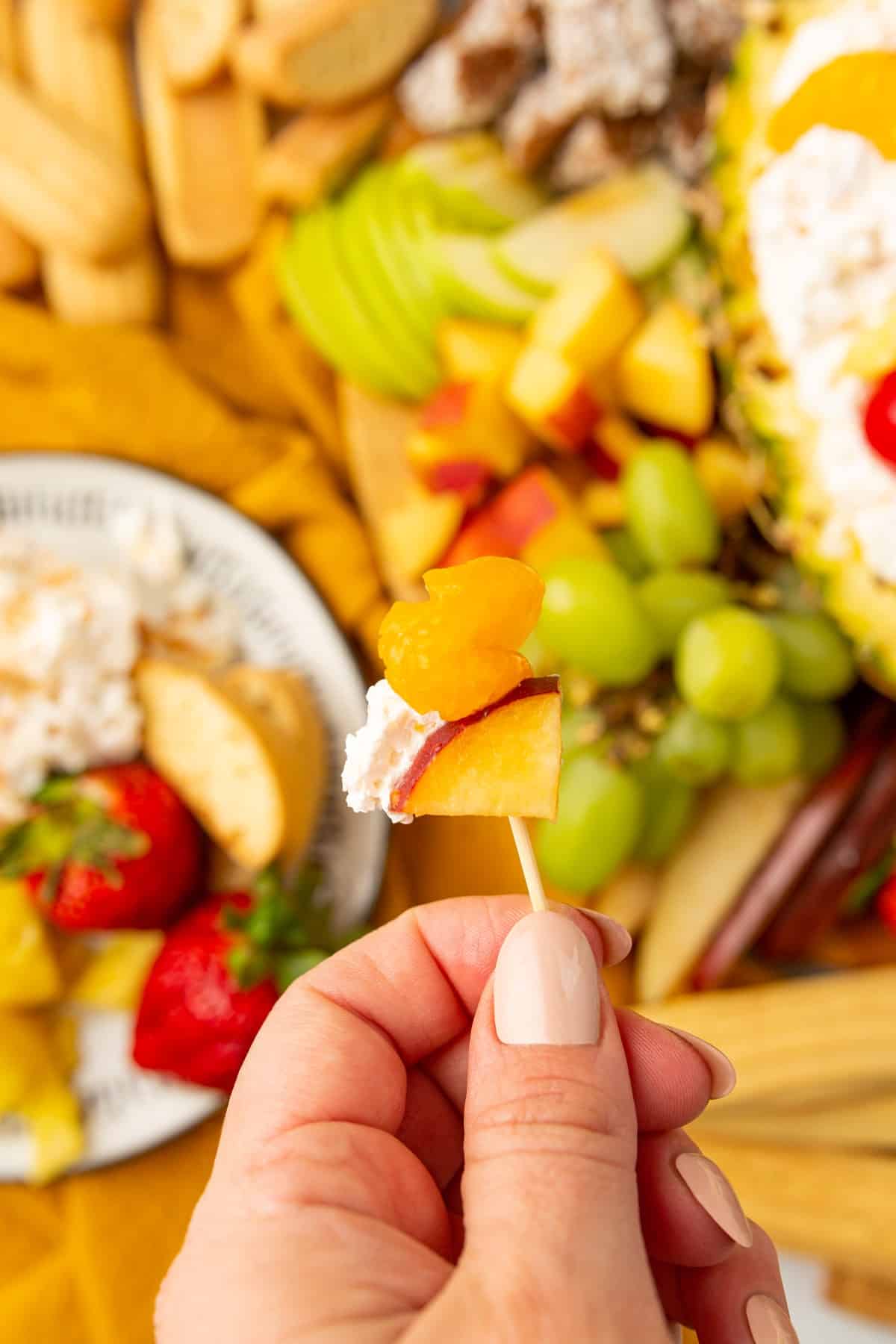 Holding fruit and dip on a toothpick. 