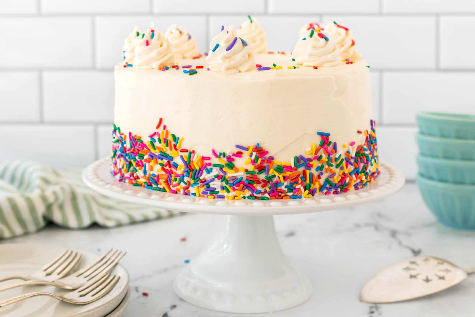 Horizontal picture of vanilla cake, iced and decorated with sprinkles. 