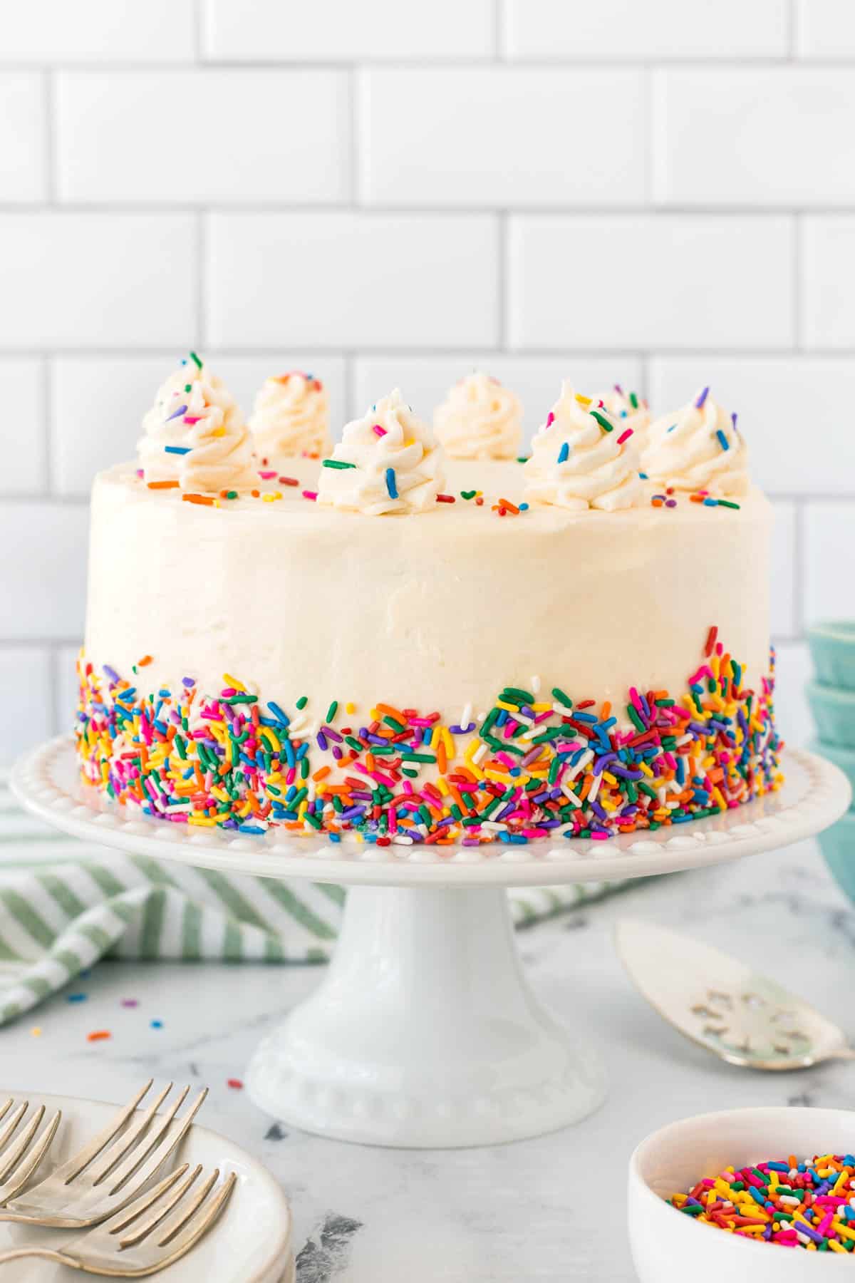 Best Vanilla Cake Recipe on a cake stand decorated with sprinkles. 